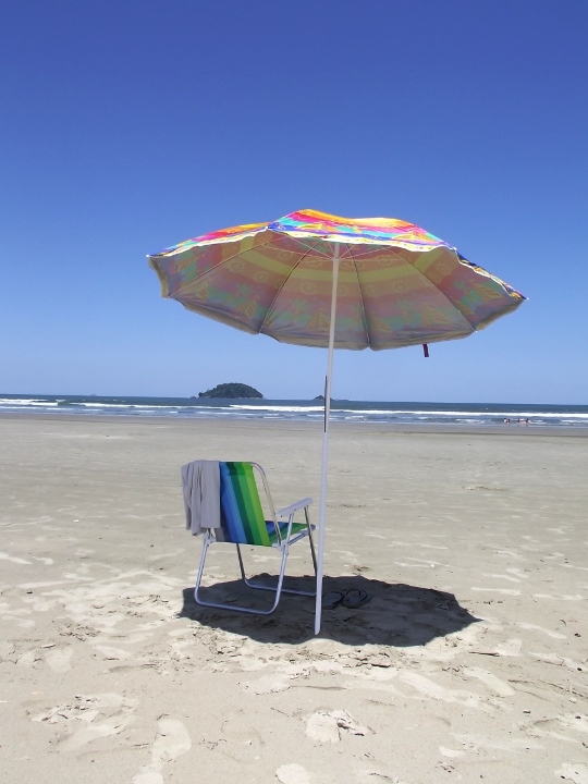 cadeira e guarda sol em praia com céu azul e mar